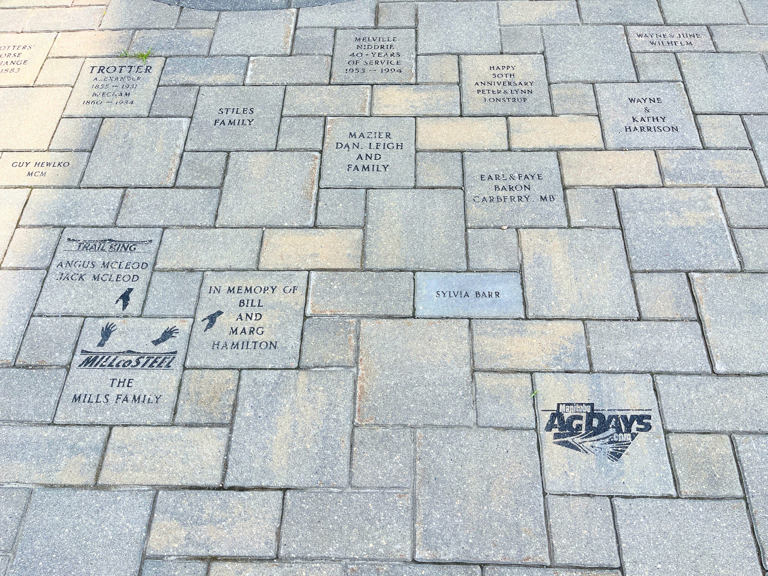 An image of a paving stones forming a walkway and engraved with the name of a local individuals and businesses. The stones appear in the walkway at The Dome Building at the Provincial Exhibition of Manitoba.
